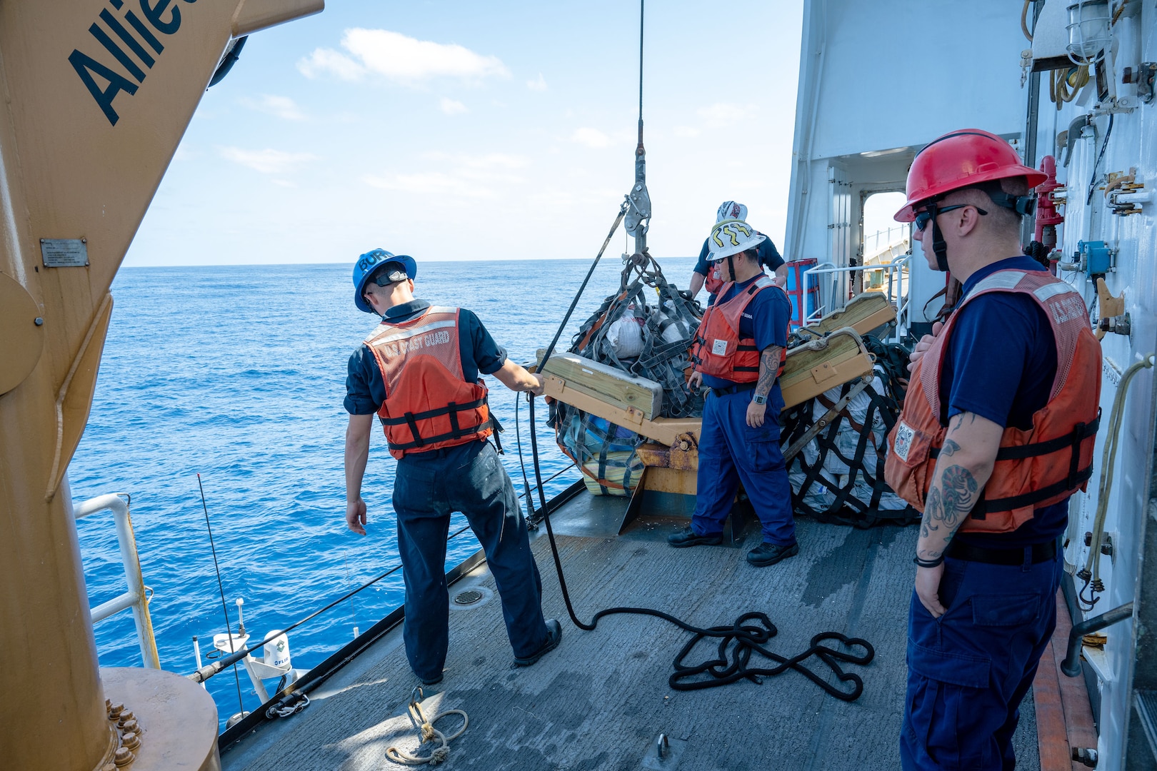 Deck crew from the U.S. Coast Guard Cutter Active (WMEC 618) prepares to transfer bales of marijuana by davit crane to the U.S. Coast Guard Cutter Waesche (WMSL 751) in the Eastern Pacific Ocean, March 25, 2023. Active and crew detected and seized over 100 bales of marijuana in international waters.    (U.S. Coast Guard photo by Petty Officer 2nd Class Justin Upshaw).