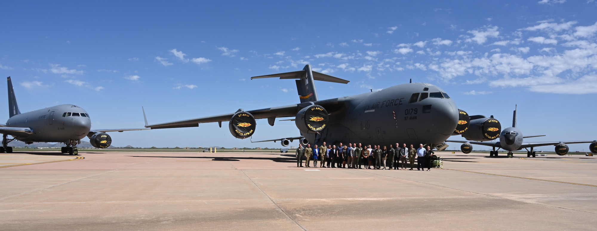97th Air Mobility Wing (AMW) homecomers, distinguished visitors, and current wing leadership pose for a photo in front of a KC-46 Pegasus, KC-135 Stratotanker, and C-17 Globemaster III at Altus Air Force Base, Oklahoma, April 14, 2023. The 97th AMW trains 70% of the United States mobility Air Force on these three platforms. (U.S. Air Force photo by Airman 1st Class Miyah Gray