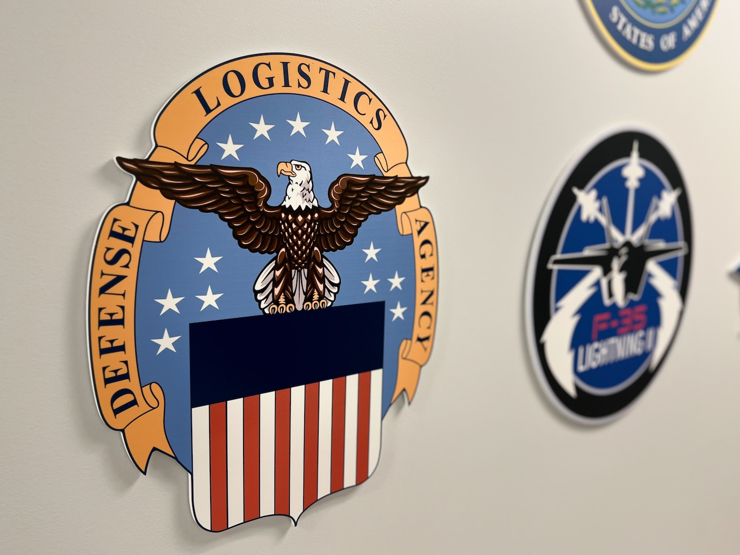 The Defense Logistics Agency and F-35 Lightning II insignias hang on a wall at the DLA Distribution San Joaquin F-35 Warehouse April 18, 2023, at DLA Distribution San Joaquin. Photo by Julian Temblador