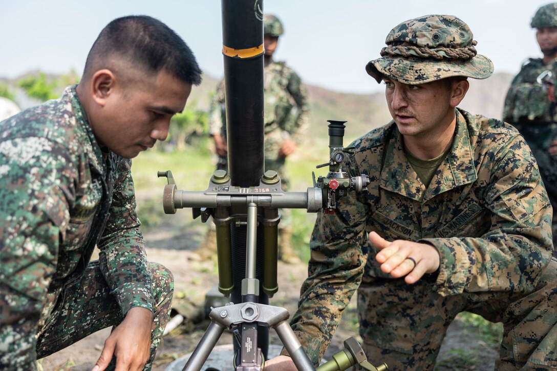 U.S. Marine Corps Private First Class Nathaniel Jackson, a mortarman with 3d Littoral Combat Team, 3d Marine Littoral Regiment, 3d Marine Division, demonstrates how to adjust the alignment of an M252 81 mm mortar system to a member of the Philippine Marine Corps during bilateral weapons familiarization during Balikatan 23 in Santa Juliana, Philippines, April 10, 2023.