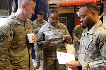 Three Airmen look at a brochure