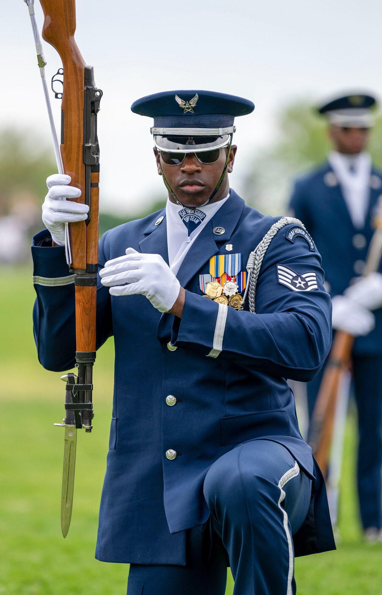Staff Sgt. Marcus Hardy of the U.S. Air Force Honor Guard Drill Team kneels with his rifle during a performance at the Joint Services Drill Exhibition, April 14, 2023, Washington Monument, Washington, D.C. The Drill Team is an elite unit of 25 Airmen who train, on average, five days a week for eight to ten hours per day to obtain their level of mastery. (U.S. Air Force photo by 2nd Lt. Brandon DeBlanc)
