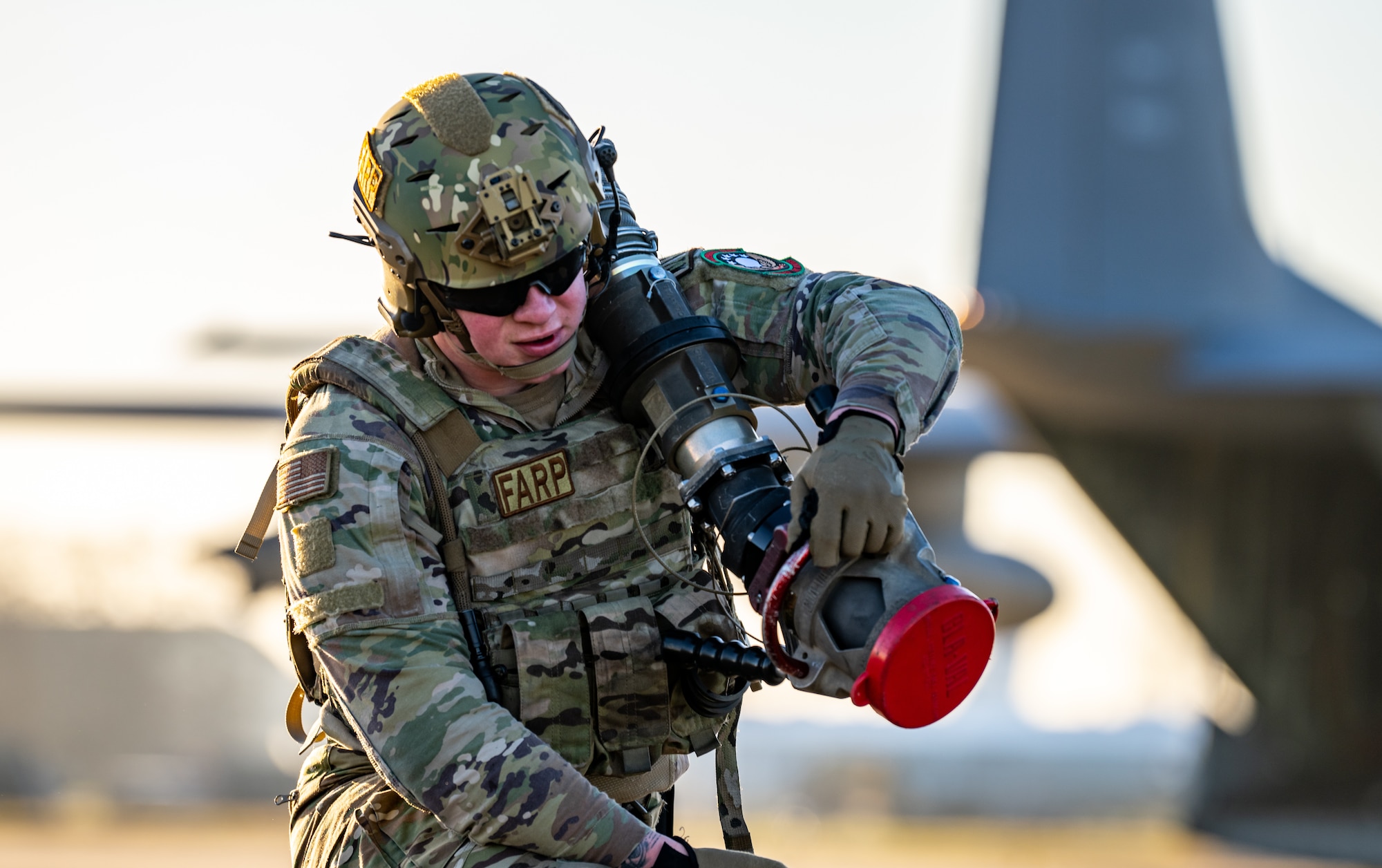 U.S. Air Force Senior Airman Benjamin Kramer, 100th Logistics Readiness Squadron forward area refueling point (FARP) specialist assigned to the 100th Air Refueling Wing, carries a fuel hose away from an MC-130J Commando II aircraft assigned to the 352nd Special Operations Wing during FARP training at Royal Air Force Mildenhall, England, Feb. 6, 2023. FARP capabilities are just one example of the agile combat employment concepts that are being trained and developed as the 352nd SOW and 100th ARW continue to lead the way in building readiness. (U.S. Air Force photo by Staff Sgt. Kevin Long)