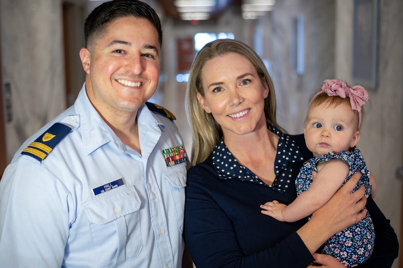 Coast Guard Lt. Coty Hall, command intelligence officer at Sector Houston-Galveston, Jenna Hall, Sector Houston-Galveston’s ombudsman and winner of the 2022 Wanda Allen-Yearout Ombudsman of the Year Award, and Adilyn, the couple’s 6-month-old daughter, pose for a portrait at the sector, April 13, 2023. Hall previously won the award in 2019 for her work as Sector Los Angeles-Long Beach’s ombudsman. (U.S. Coast Guard photo by Petty Officer 1st Class Corinne Zilnicki)