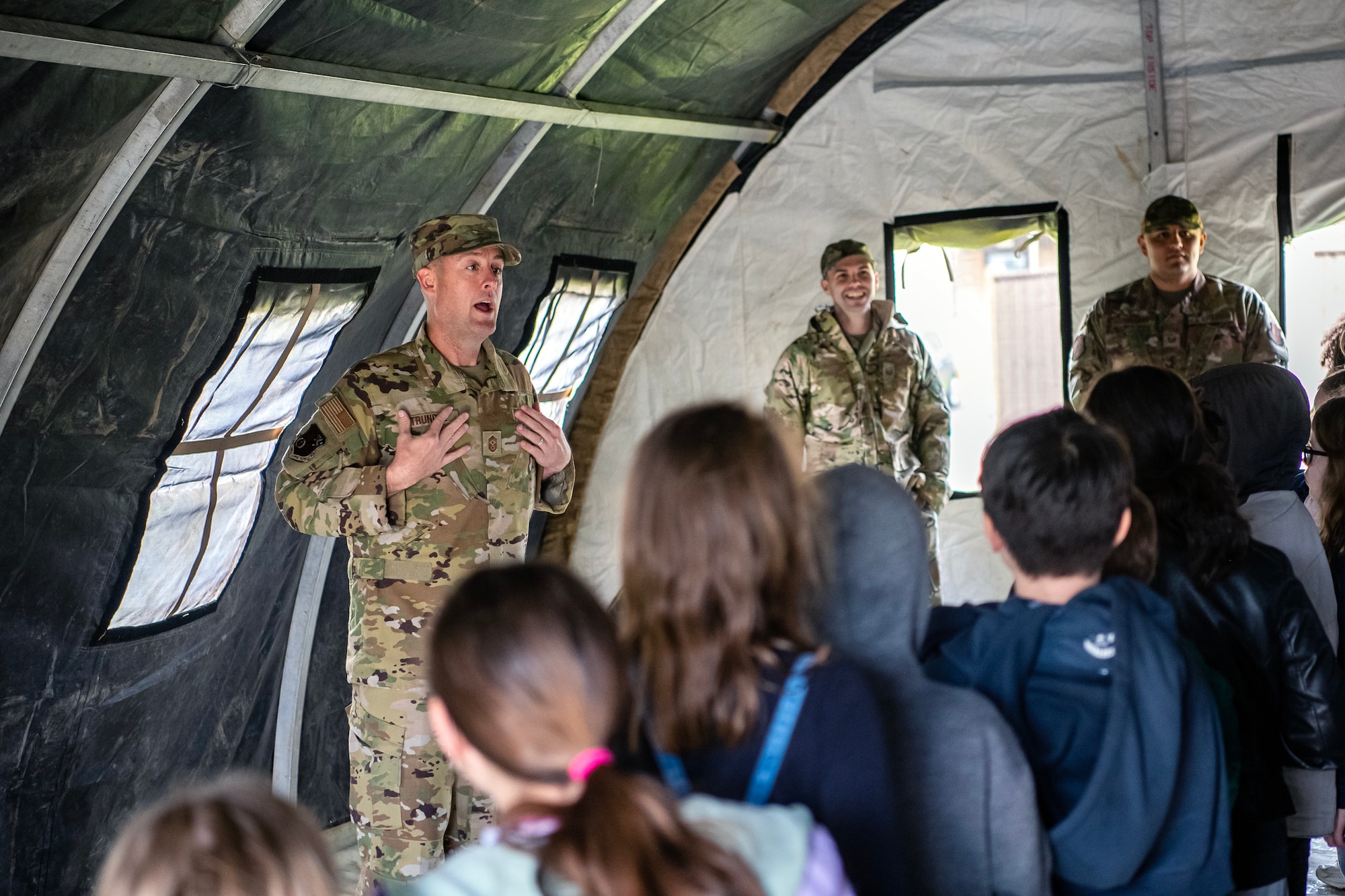 U.S. Air Force Chief Master Sgt. Joshua Trundle, 501st Combat Support Wing command chief, speaks to Alconbury Elementary school students during Camp Kudos at RAF Alconbury, England, April 14, 2023. The camp gave students the opportunity to experience and learn about various aspects of deployment preparation and the wing mission. (U.S. Air Force photo by Staff Sgt. Eugene Oliver)