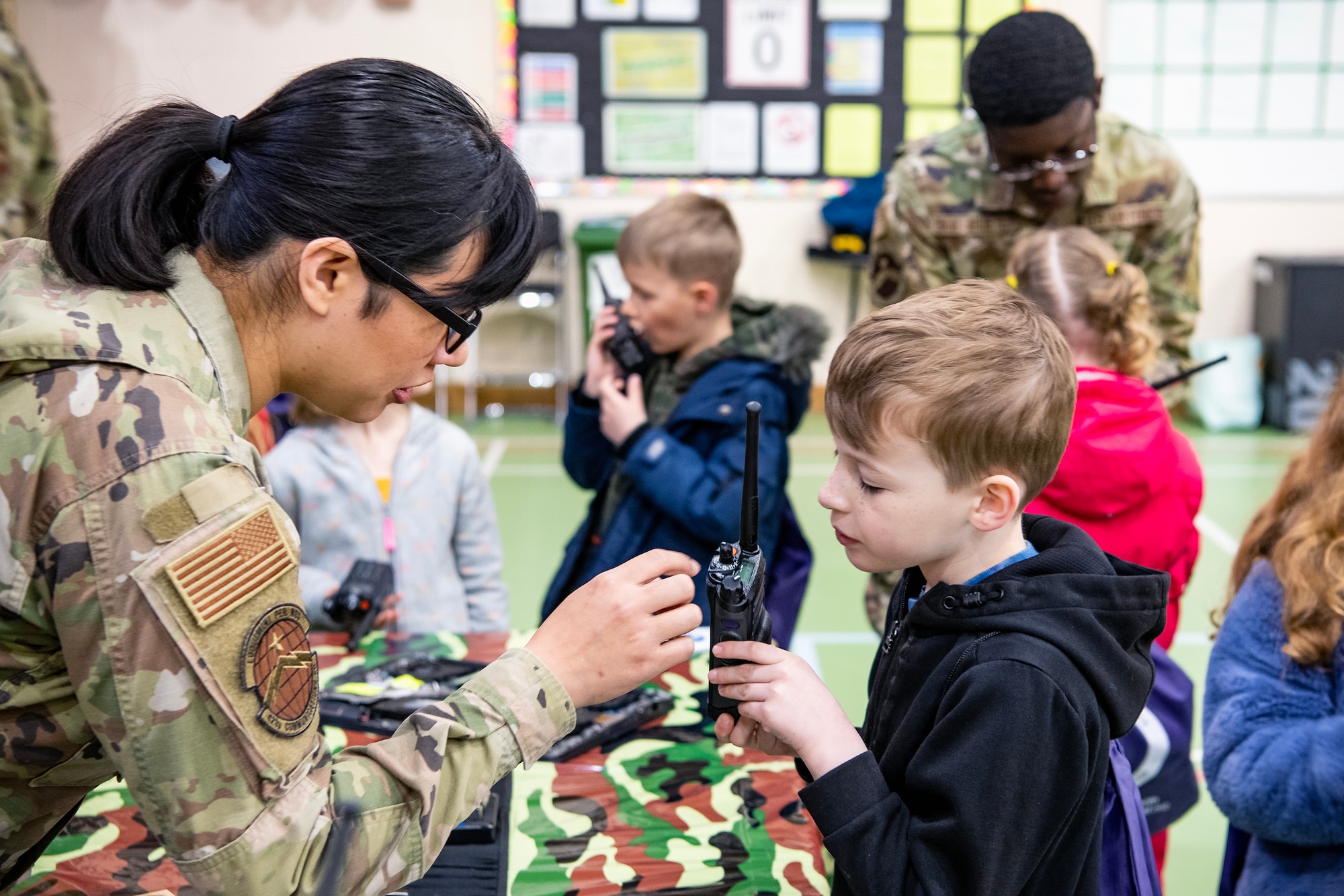 Airmen from the 423d Communications Squadron demonstrate how to use a walkie talkies to Alconbury Elementary 
School students during Camp Kudos at RAF Alconbury, England, April 14, 2023. The camp gave students the opportunity to experience and learn about various aspects of deployment preparation and the wing mission. (U.S. Air Force photo by Staff Sgt. Eugene Oliver)
