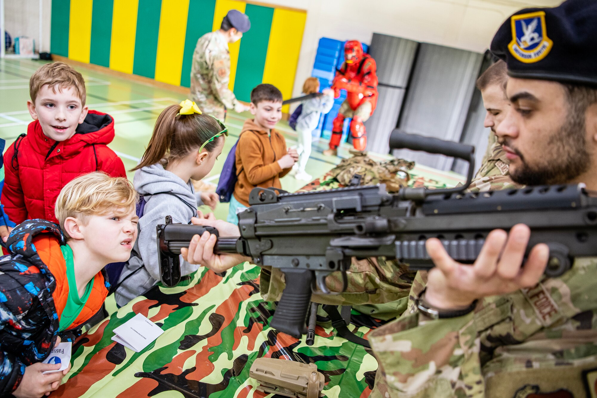 A 423d Security Forces Squadron Airman displays a M249 Automatic Rifle to Alconbury Elementary School students during Camp Kudos at RAF Alconbury, England, April 14, 2023. The camp gave students the opportunity to experience and learn about various aspects of deployment preparation and the wing mission. (U.S. Air Force photo by Staff Sgt. Eugene Oliver)