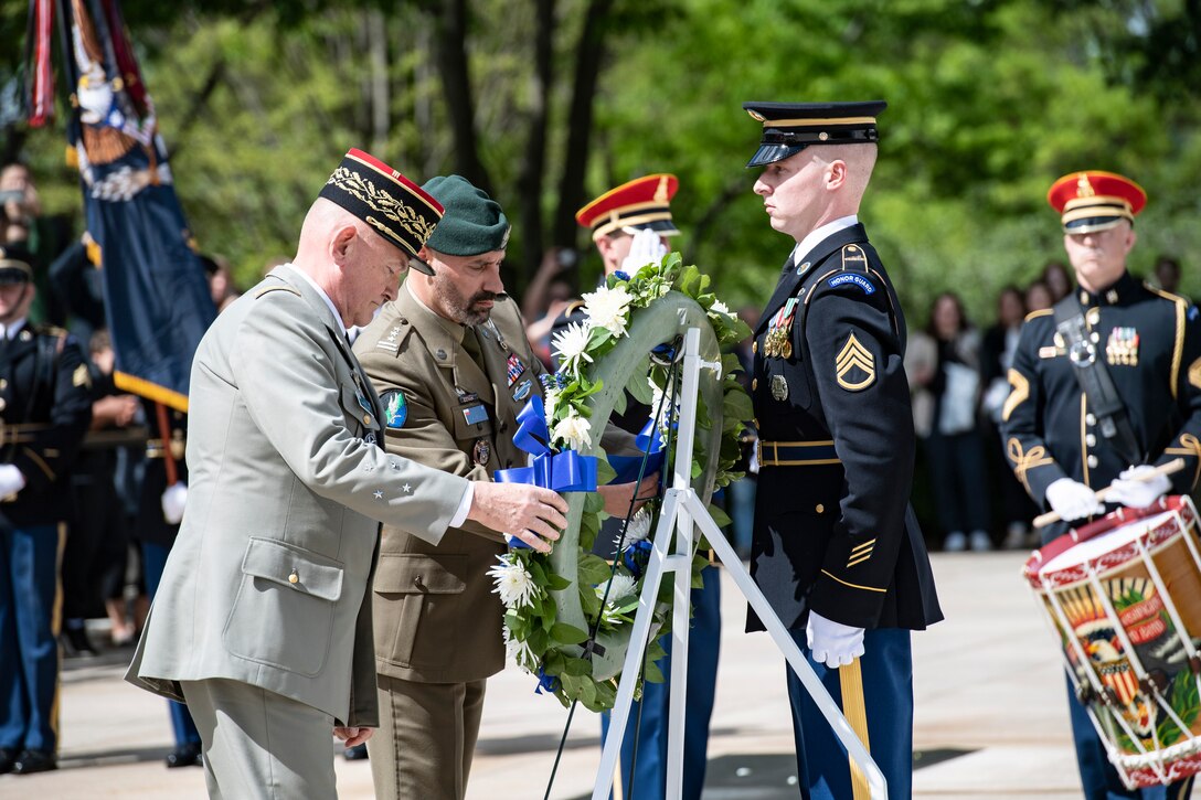 Two officers arrange a wreath during a formal ceremony.