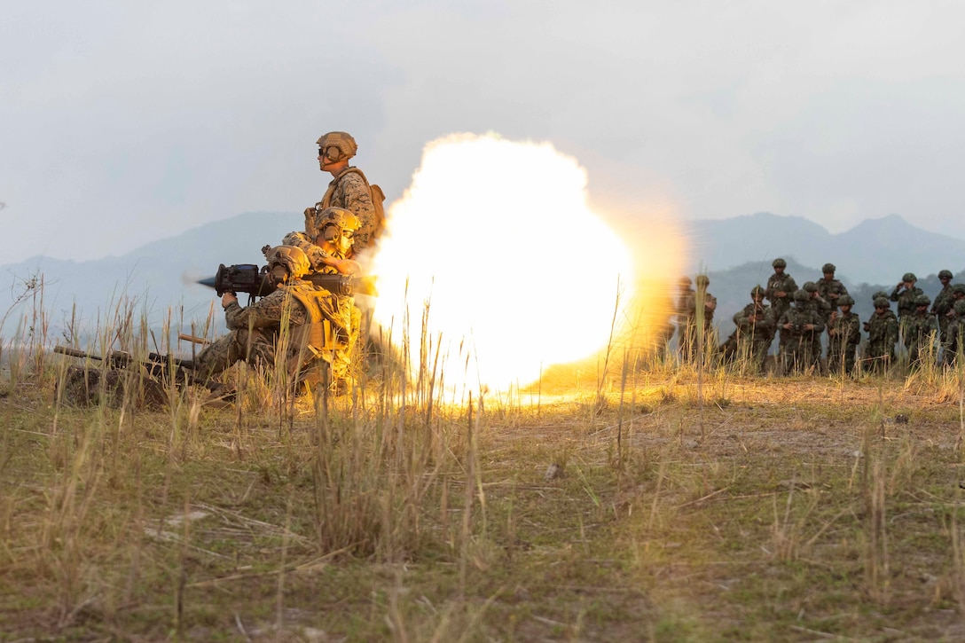 Marines launch an over the shoulder weapon as others watch.