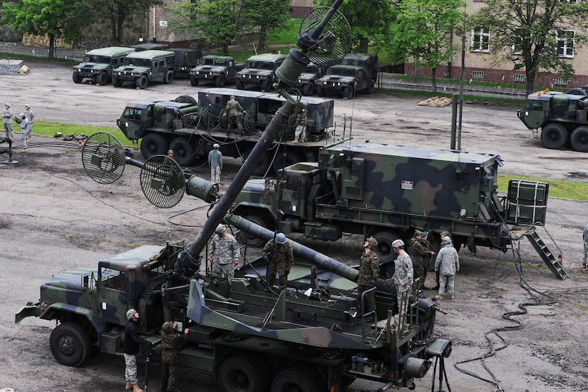 Military personnel work around tactical vehicles.