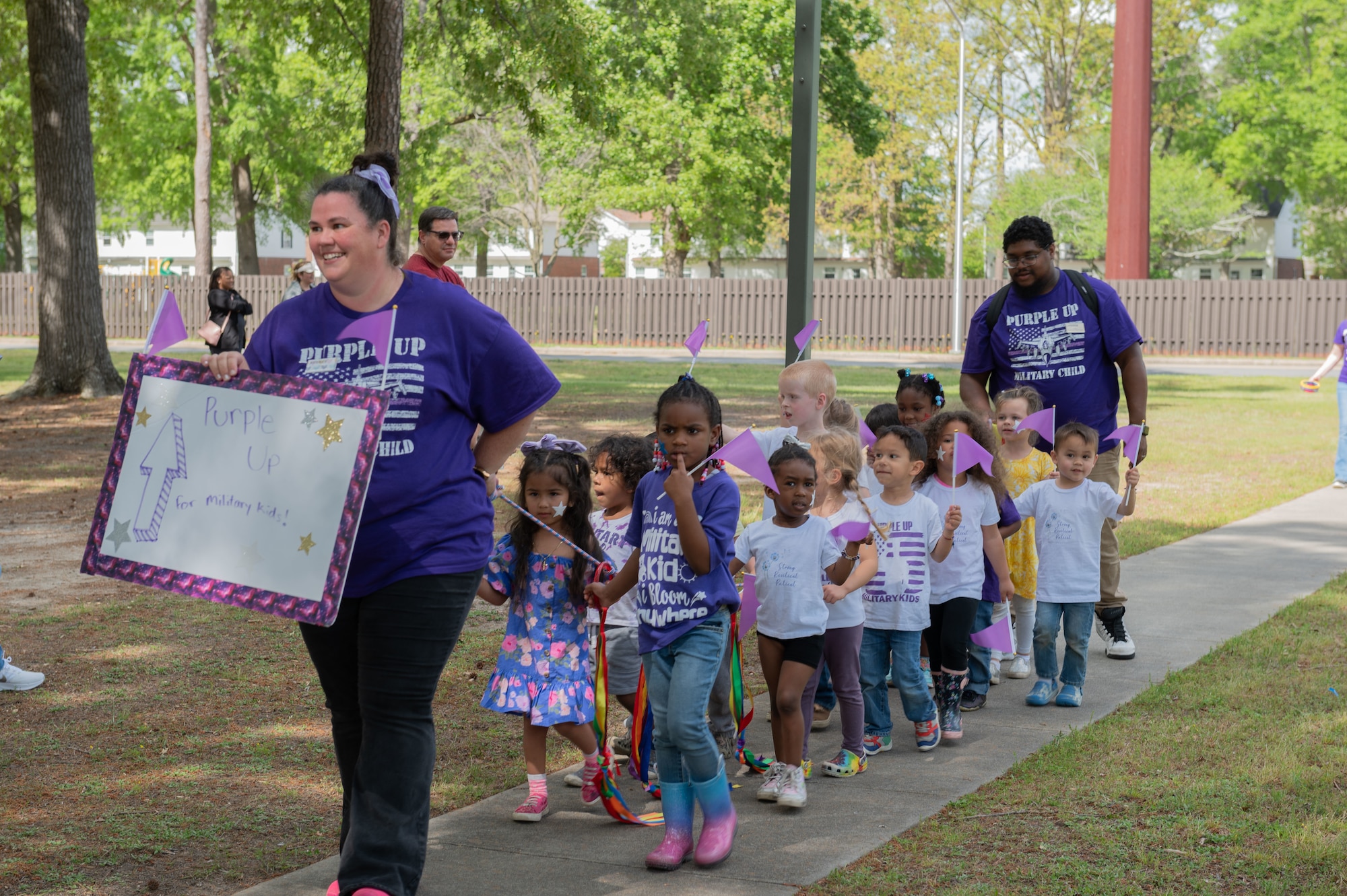 Teachers from of the 4th Force Support Squadron march with children from the Child Development Center during the Purple Up Parade to celebrate the Month of the Military Child at Seymour Johnson Air Force Base, North Carolina, April 14, 2023. The parade was held to honor and celebrate children of military members serving at home and overseas. (U.S. Air Force photo by Rebecca Sirimarco-Lang)