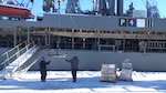 two people on a pier with snow offloading supplies from a ship
