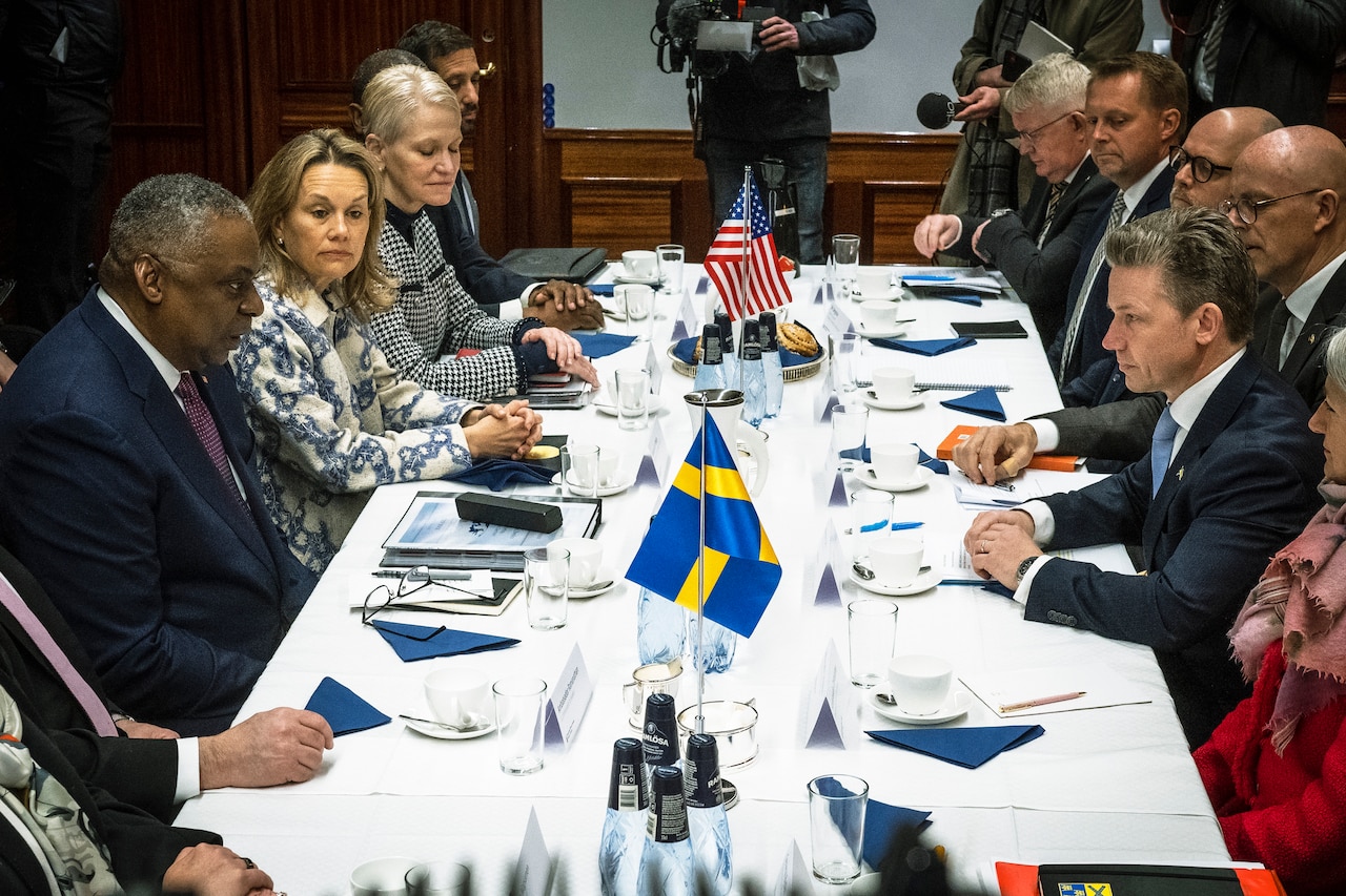 A group of men and women sit around a conference table.