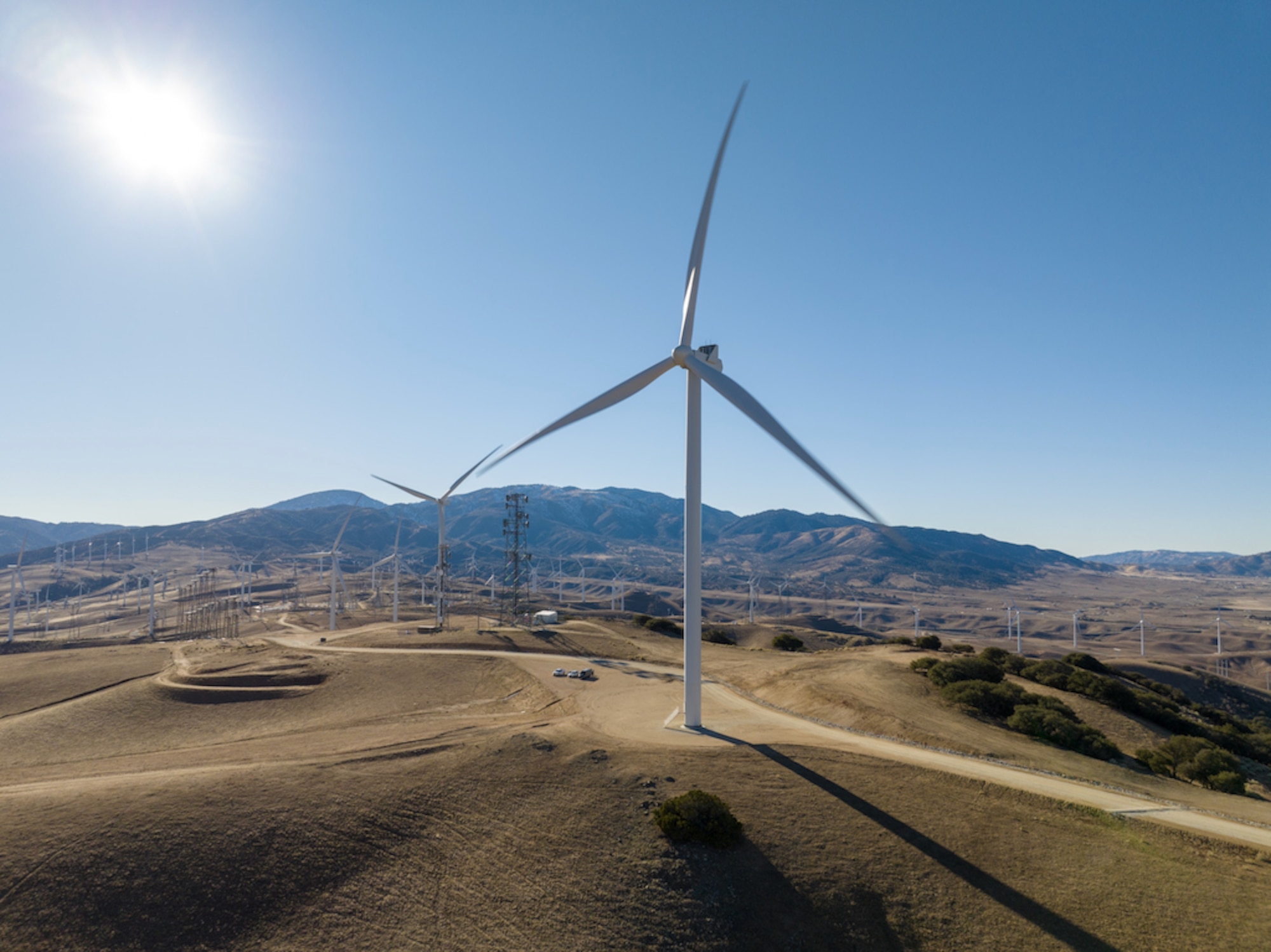 Wind turbine sits in the foreground at Edwards AFB in California flanked by California hillside.