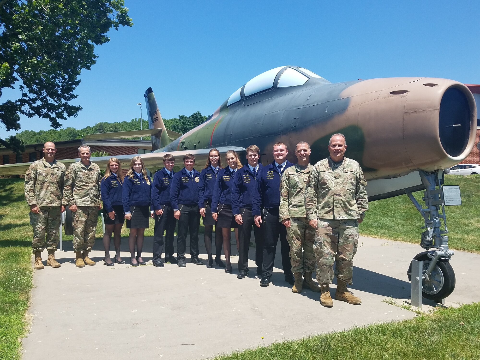 Iowa FFA Association state officers and U.S. Air National Guard Airmen of Iowa Joint Force Headquarters pose for a photo in front of a static U.S. Air Force F-34 Thunderstrike.