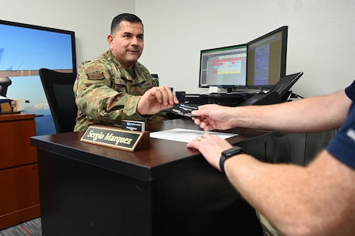 U.S. Air Force Master Sgt. Sergio Marquez, 353rd Recruiting Squadron in-service recruiter, hands his business card to a potential recruit at Davis-Monthan Air Force Base, Ariz., April 18, 2023. Marquez assists service members with Air Force Reserve matters or concerns. (U.S. Air Force photo by Staff Sgt. Abbey Rieves)