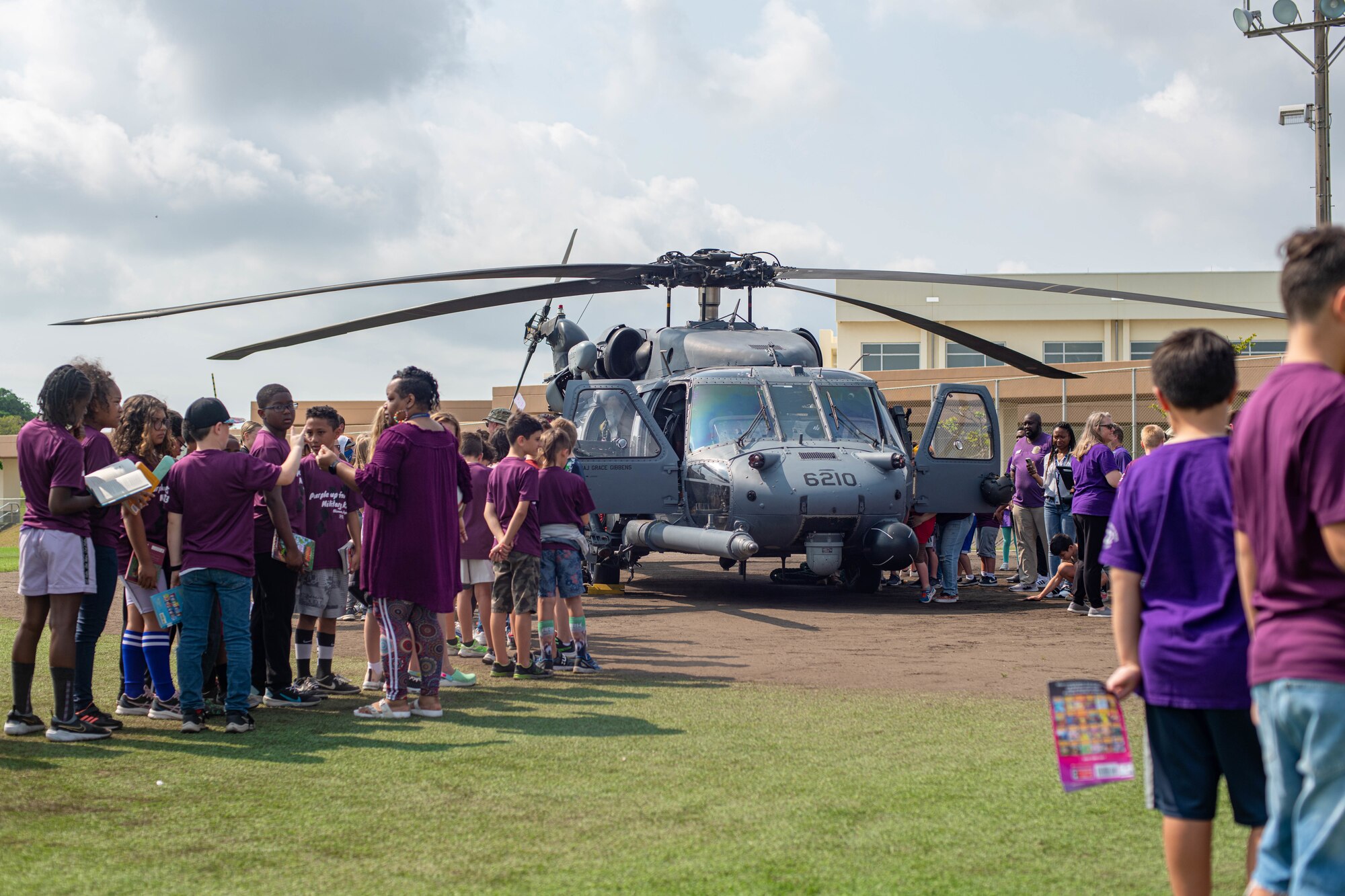 Kids wait by a helicopter.