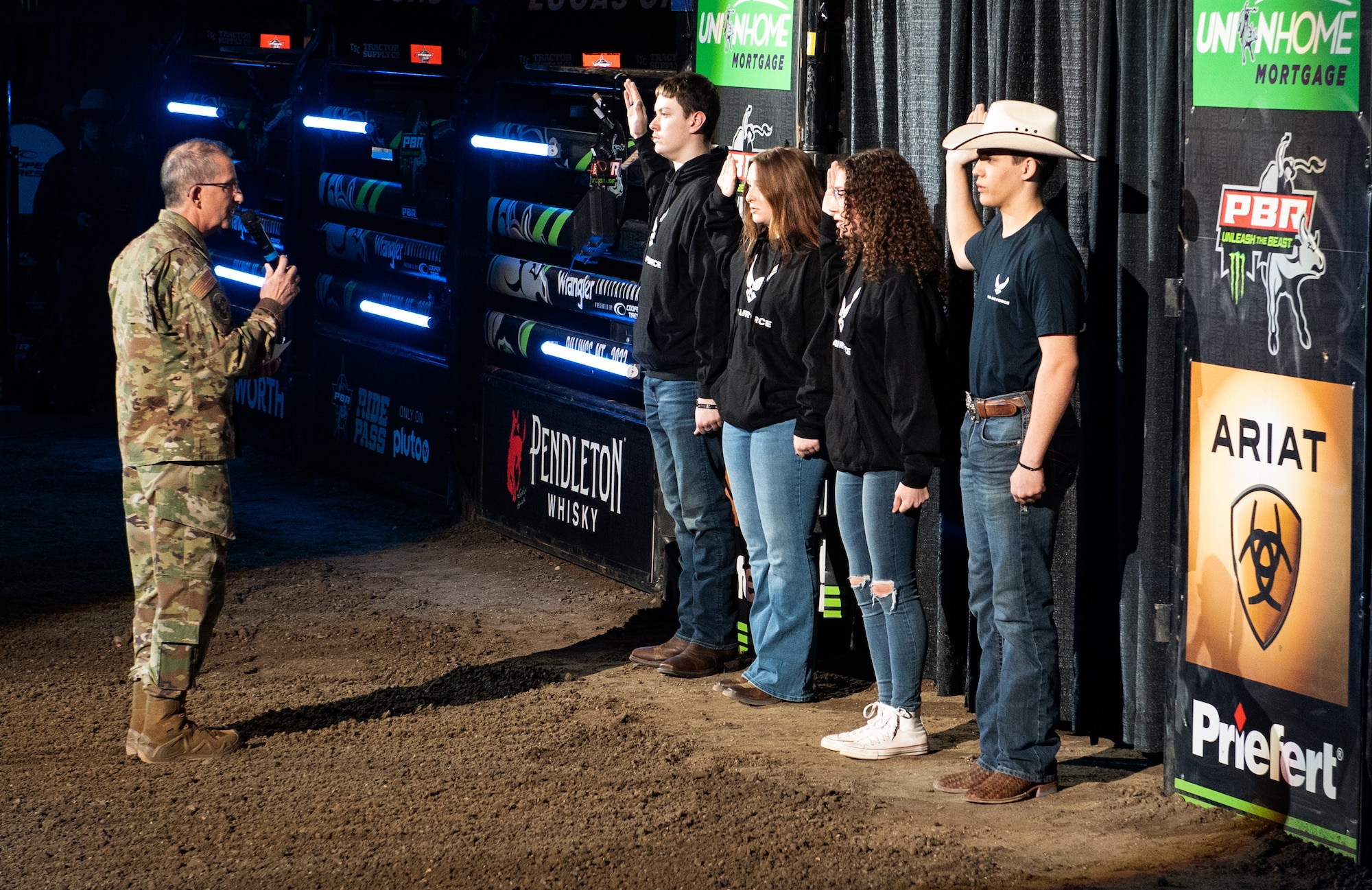 Brig. Gen. Thomas Mora, Montana Air National Guard director of staff, issues the Oath of Enlistment to 4 delayed enlistment program applicants in front of the crowd at the Professional Bull Riders event “Unleash The Beast’s Cooper Tires Invitational” in Billings, Montana, April 15, 2023.
