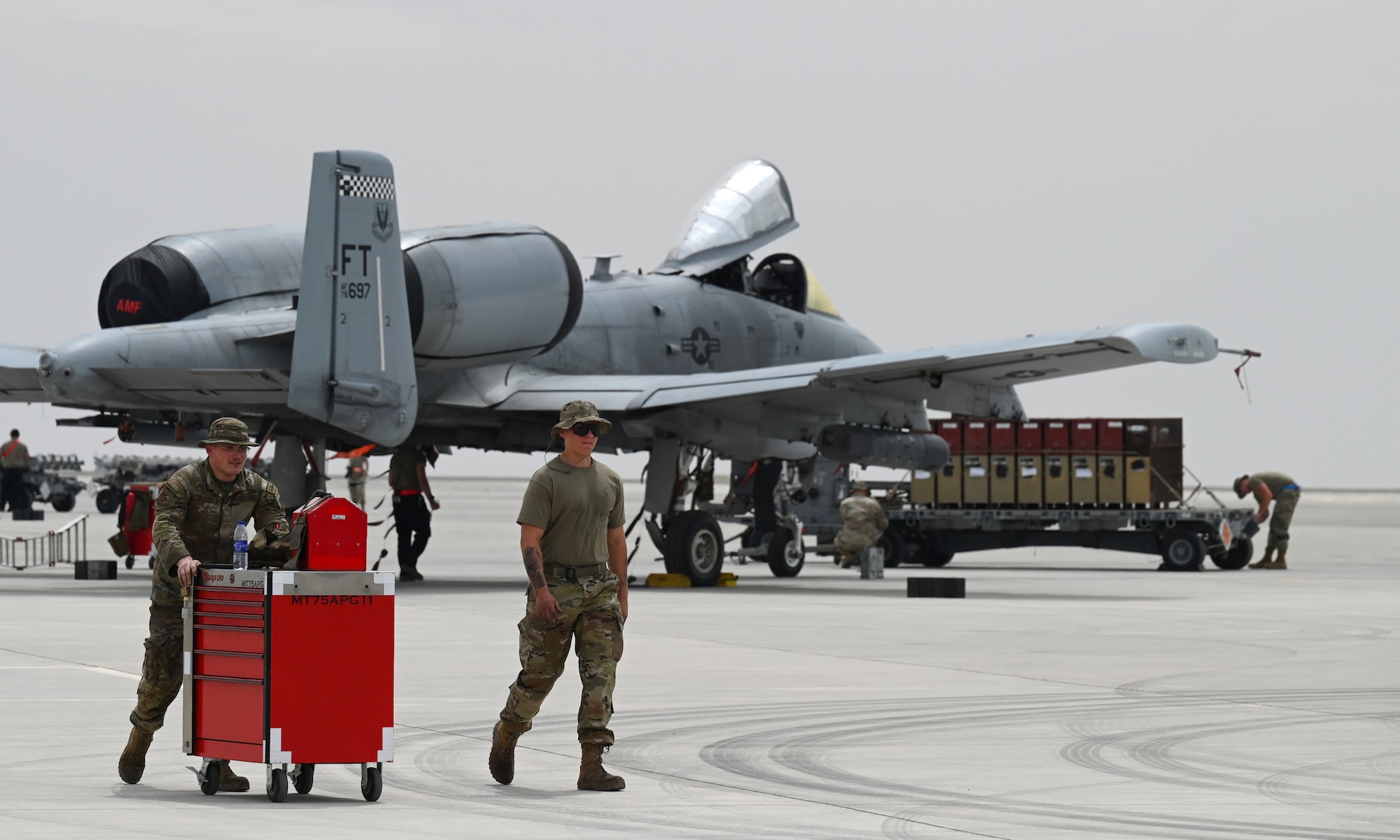 U.S. Air Force Senior Airman Peyton McAdams and Airman 1st Class Mayson Browning, 75th Expeditionary Fighter Generation Squadron crew chiefs, walk down the flight line after preparing U.S. Air Force A-10 Thunderbolt IIs to receive munitions at Al Dhafra Air Base, United Arab Emirates, April 18, 2022. The loading of these munitions represents another step forward in the deployment of the A-10 to the U.S. Central Command area of responsibility, which offers the opportunity for 9th Air Force (Air Forces Central). to experiment with CAS capabilities in order to achieve the most robust, diverse force possible. Ninth AF (AFCENT) is committed to ensuring security and stability alongside our partners in the U.S. Central Command area of responsibility.  (U.S. Air Force photo by Tech. Sgt. Alex Fox Echols III)