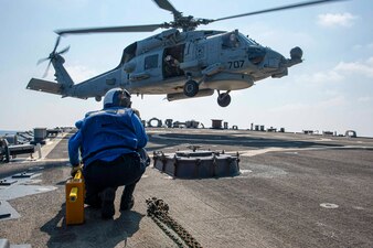 Cryptologic Technician (Collection) 1st Class Lynea Arriaga observes an MH-60R Seahawk helicopter, from the "Grandmasters" of helicopter maritime strike squadron (HSM) 46, approach the flight deck of the guided-missile destroyer USS Paul Hamilton (DDG 60), April 16, 2023 in the Arabian Sea.