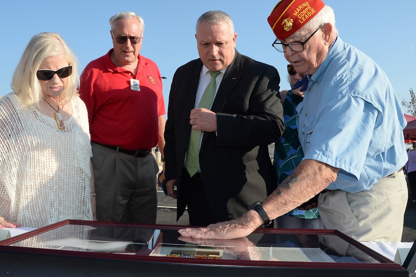 Four people look down at a military display case.