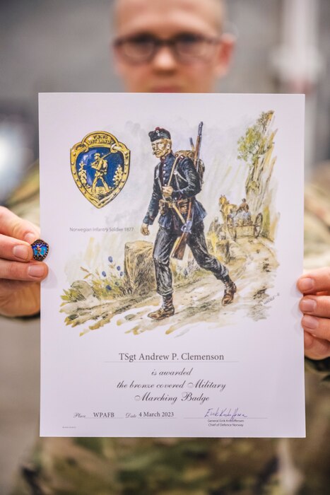 Tech. Sgt. Andrew Clemenson, U.S. Air Force Band of Flight member, displays his certificate of completion and pin April 7 for meeting the standards in the Norwegian Foot March at Wright-Patterson Air Force Base, Ohio.