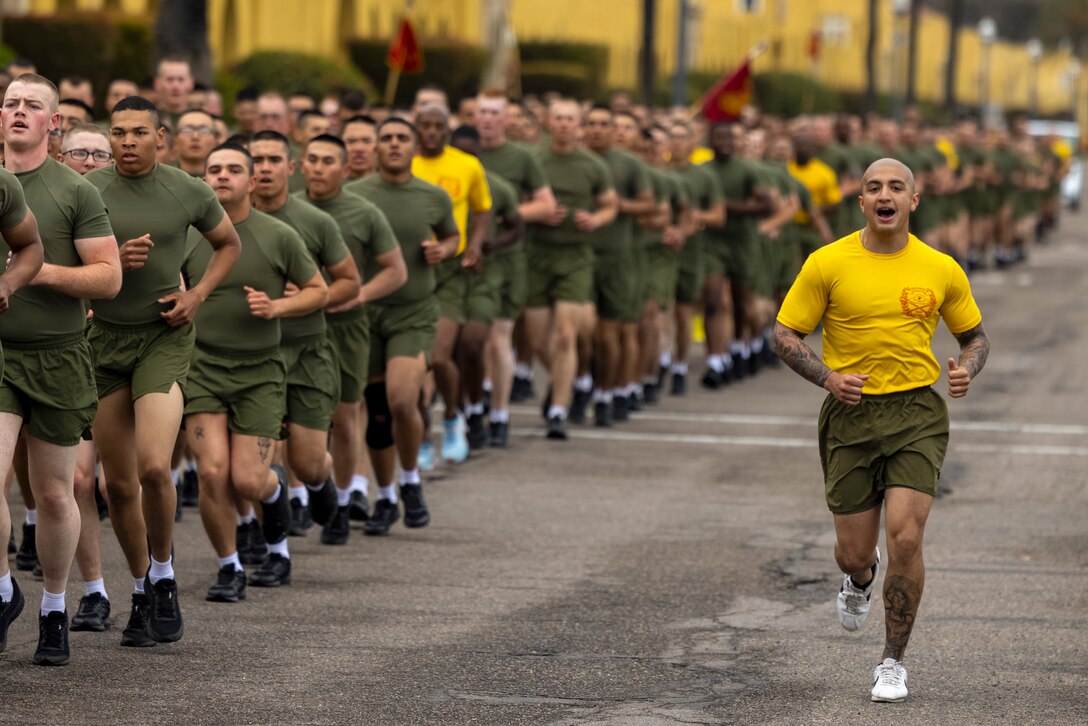 A Marine shouts while running next to fellow Marines in formation.