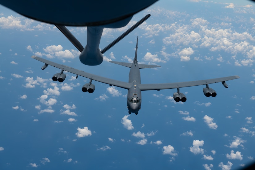 A military aircraft positions itself toward the boom area of another aircraft for refueling.