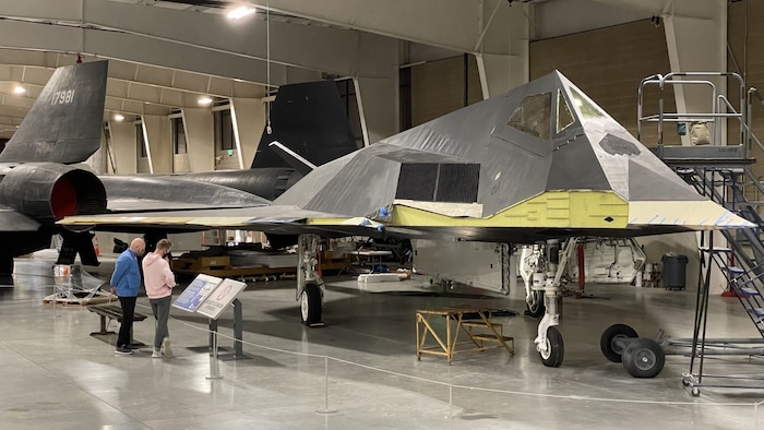 Two people looking at the F-117A without wings at Hill's Aerospace Museum