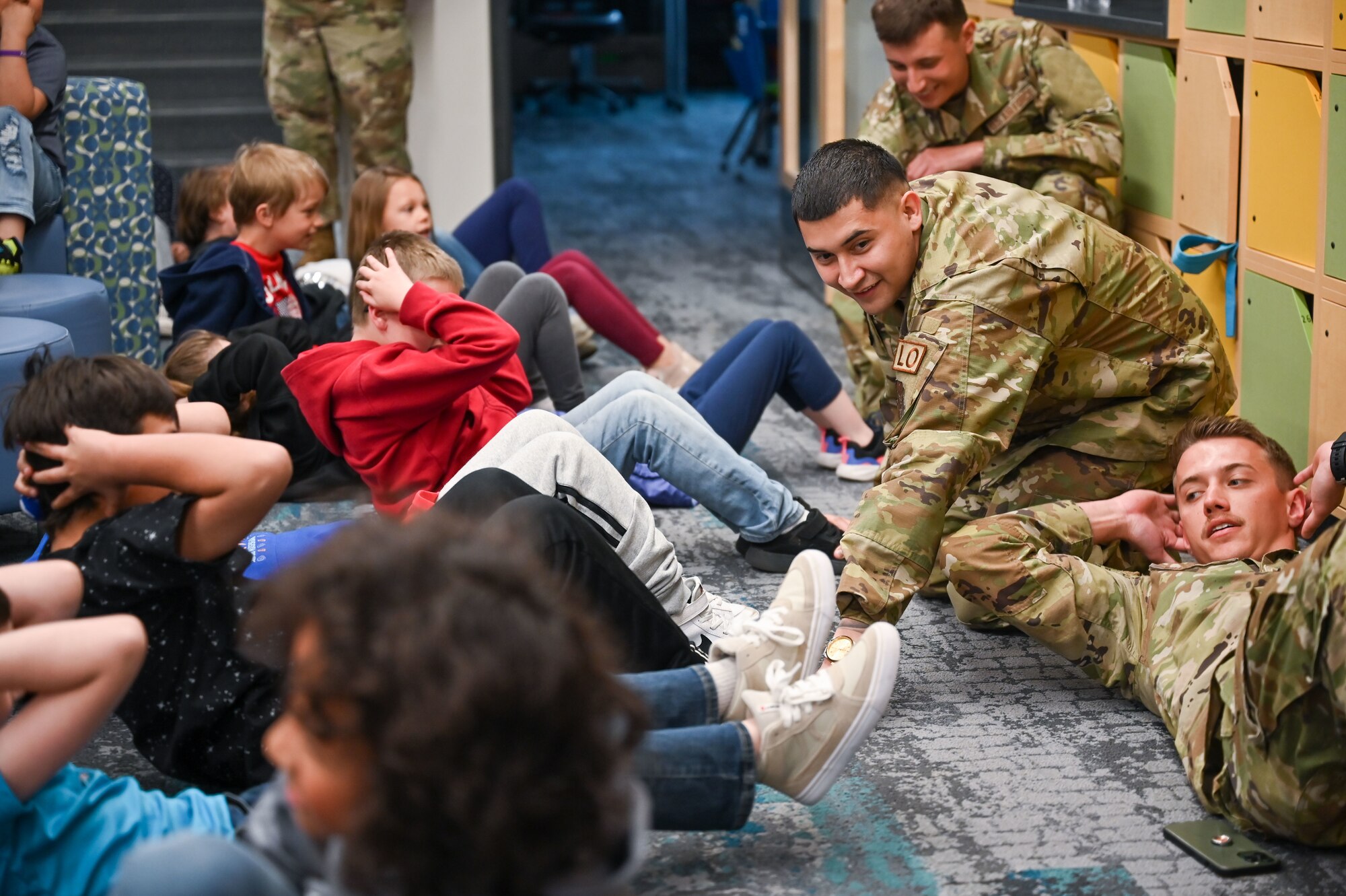(Middle right) Senior Airman Dominic Alire, 419th Maintenance Squadron, helps South Clearfield Elementary students with sit-ups April 18, 2023, in Clearfield, Utah. The Airmen visited the school to engage with the community during the Month of the Military Child. (U.S. Air Force photo by Cynthia Griggs)