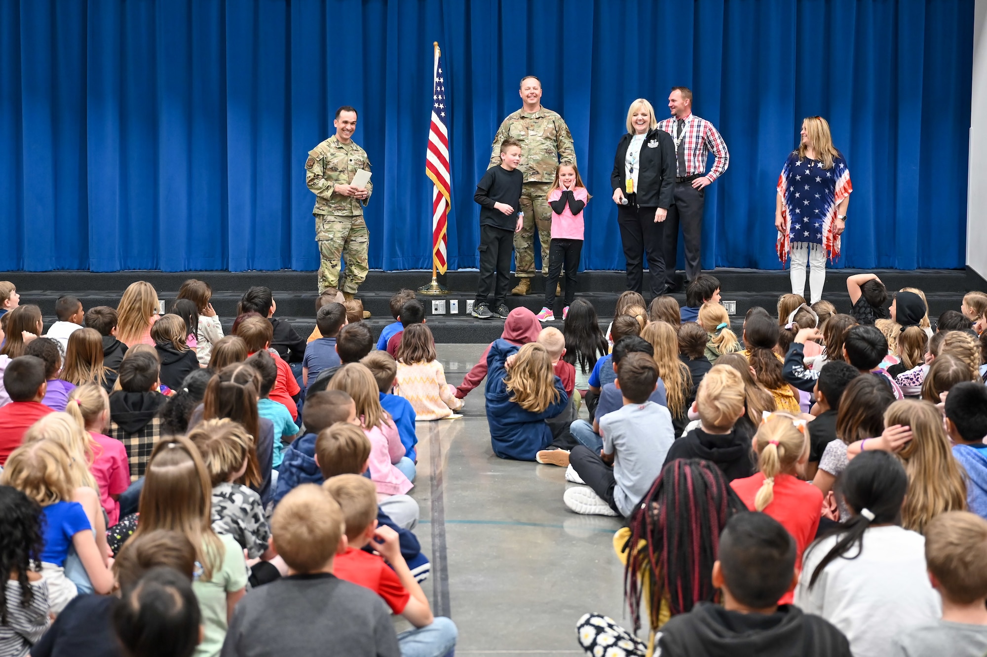 (Left) Lieutenant Col. Austin Gruber, 75th Logistics Readiness Squadron commander, and Chief Master Sgt. Bradley West, 75th LRS senior enlisted leader, present letters and patches to children at a South Clearfield Elementary assembly April 18