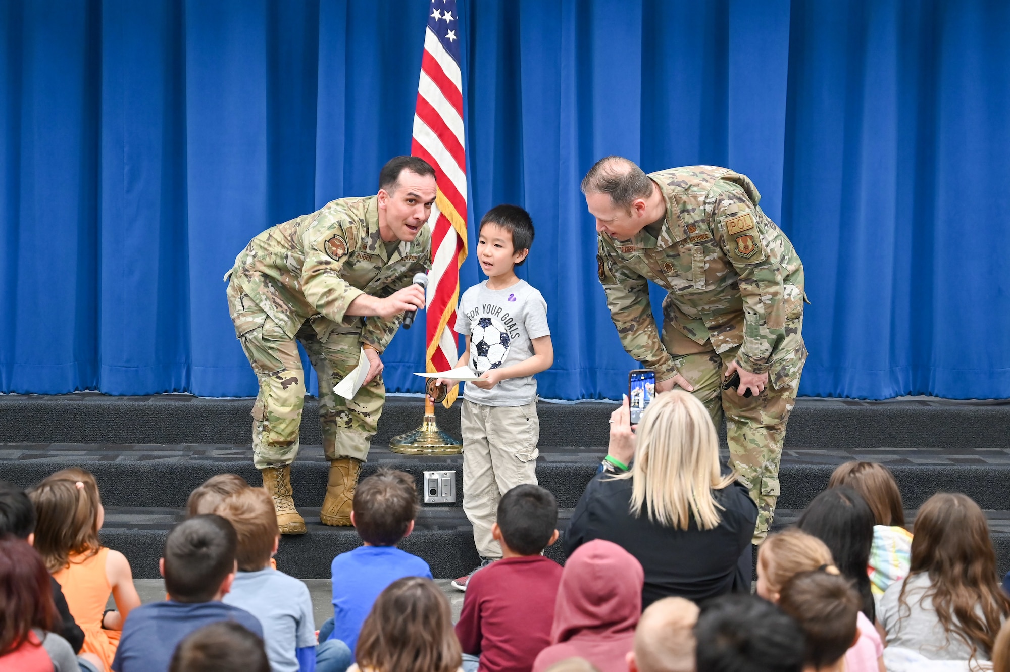 (Left) Lieutenant Col. Austin Gruber, 75th Logistics Readiness Squadron commander, and Chief Master Sgt. Bradley West, 75th LRS senior enlisted leader, present letters and patches to children at a South Clearfield Elementary assembly April 18