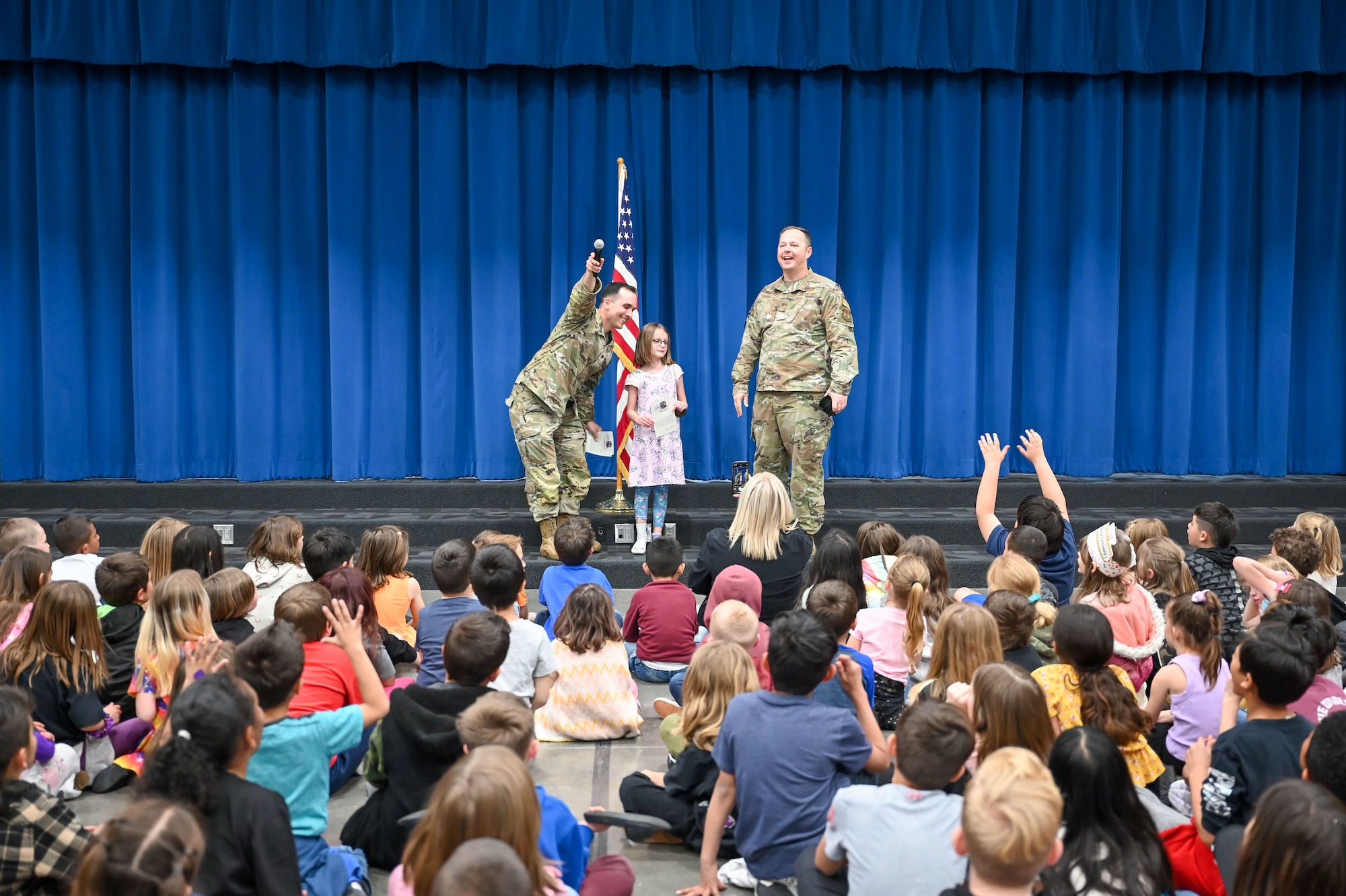 (Left) Lieutenant Col. Austin Gruber, 75th Logistics Readiness Squadron commander, and Chief Master Sgt. Bradley West, 75th LRS senior enlisted leader, present letters and patches to children at a South Clearfield Elementary assembly April 18