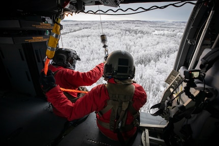 Alaska Army Guard Staff Sgt. Brad McKenzie, left, a crew chief and hoist operator, assists Spc. Matthew Tucker, a flight medic, both assigned to Golf Company, 2-211th General Support Aviation Battalion, as he prepares to be lowered from an Alaska Army National Guard HH-60M Black Hawk helicopter on Joint Base Elmendorf-Richardson, Alaska, Jan. 10, 2023. The same team worked together on April 19, 2023, to rescue an injured backcountry skier from a mountainside near Girdwood, Alaska, after an avalanche pulled him 800 to 1000 feet down the face.