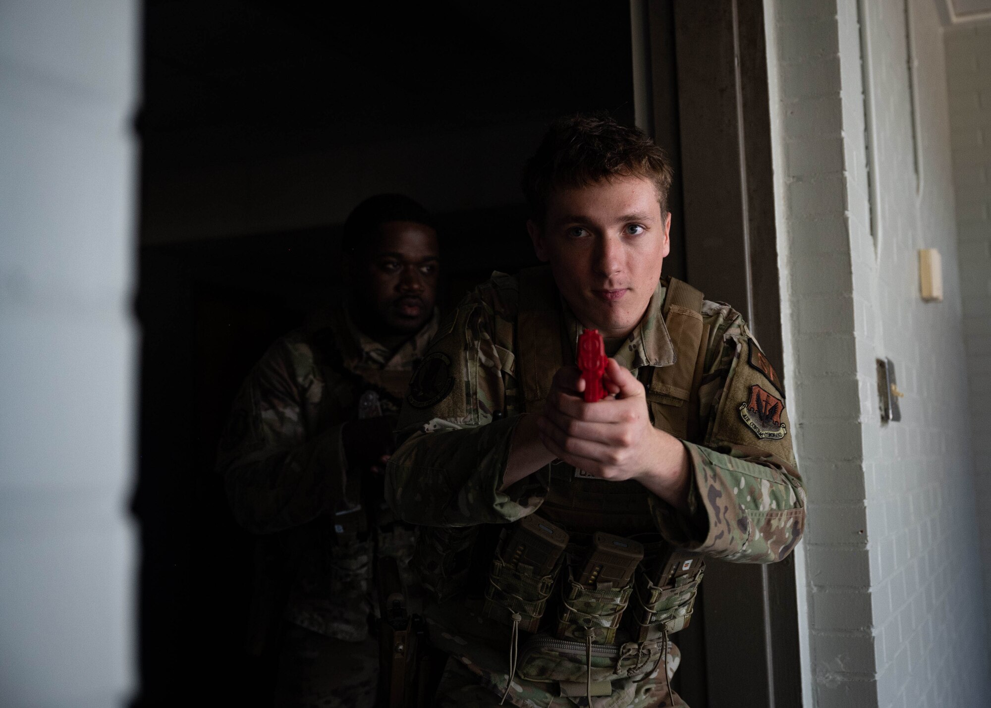 Airman with a mock pistol comes around a corner in close quarters