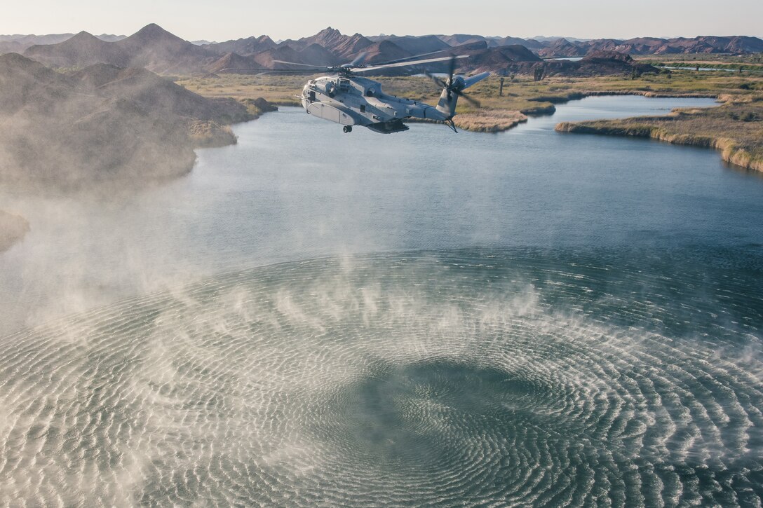 A helicopter flies above water.