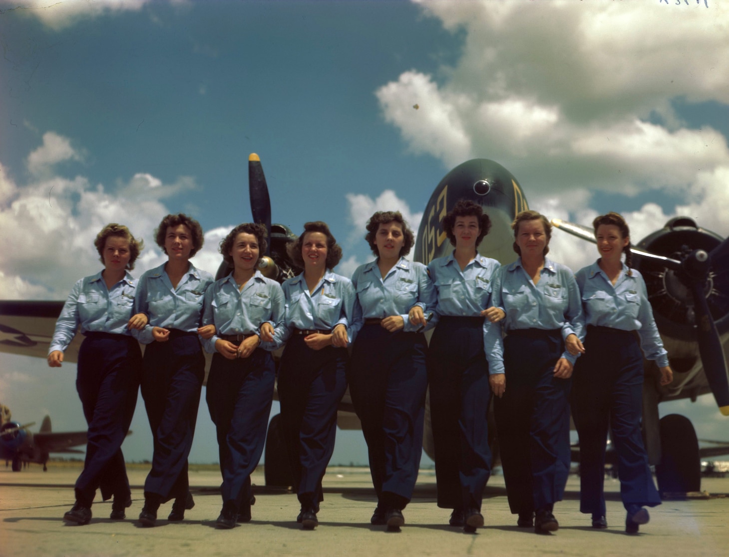 Eight WASPs photographed along the ramp at the Army Air Force Training Command’s Advanced single engine pilot school at Foster Field, Victoria, Texas. Left to right: Pauline S. Cutler (Cleveland, OH); Dorothy Ehrhardt (Bridgewater, MA); Jennie M. Hill (Harvey, IL); Etta Mae Hollinger (Paola, KS); Lucille R. Cary (Joliet, IL); Jane B. Shirley (Brownfield, TX); Dorothy H. Beard (Sacramento, CA); and Kathryn L. Boyd (Weatherford, TX). Image courtesy National Archives and Records Administration (342-C-K3616).