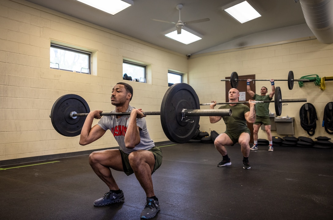 U.S. Marines raise barbells over their heads during the “Prevention” event while participating in the first Training and Education Command Fittest Instructor Competition on Marine Corps Base Quantico, Virginia, April 14, 2023. Marines had nine minutes to complete as many repetitions as possible of thrusters and wall walks. (U.S. Marine Corps photo by Lance Cpl. Joaquin Dela Torre)