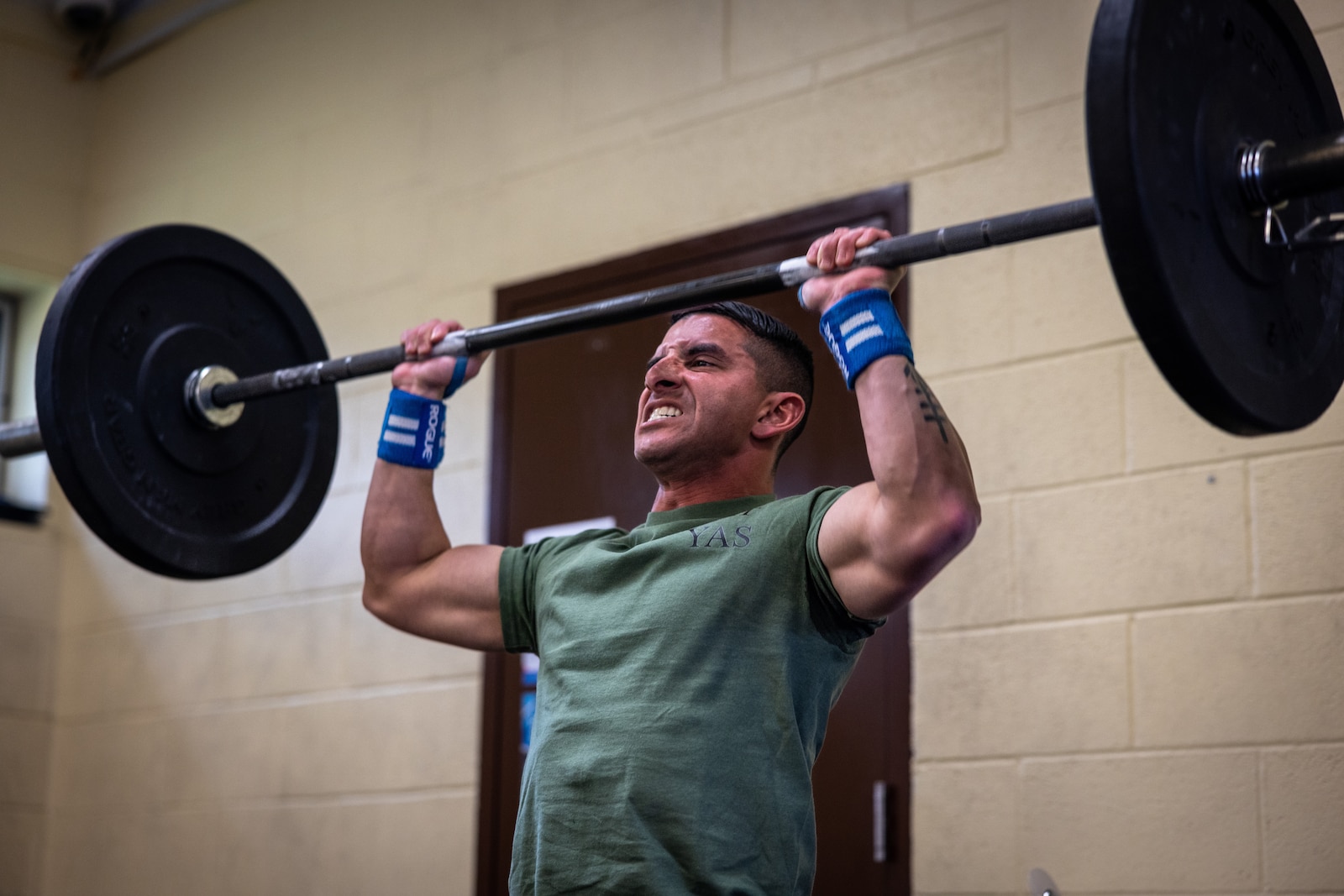 U.S. Marine Corps Sgt. Oscar Riverakirkconnell, a platoon sergeant with Assault Amphibian School Battalion, Camp Pendleton, California, raises a barbell over his head during the “Prevention” event while participating in the first Training and Education Command Fittest Instructor Competition on Marine Corps Base Quantico, Virginia, April 14, 2023. Marines had nine minutes to complete as many repetitions as possible of thrusters and wall walks. (U.S. Marine Corps photo by Lance Cpl. Joaquin Dela Torre)
