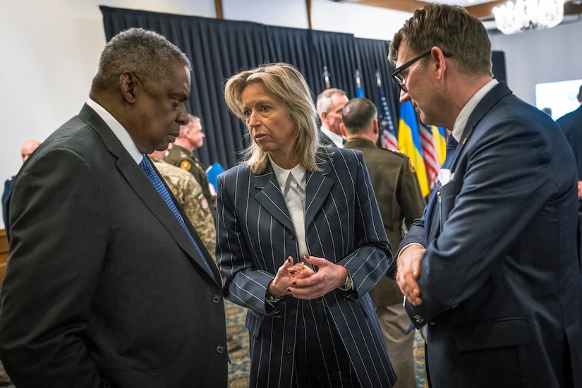 Three people stand together and talk.