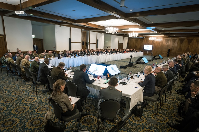 A large group of people sit around a long table.