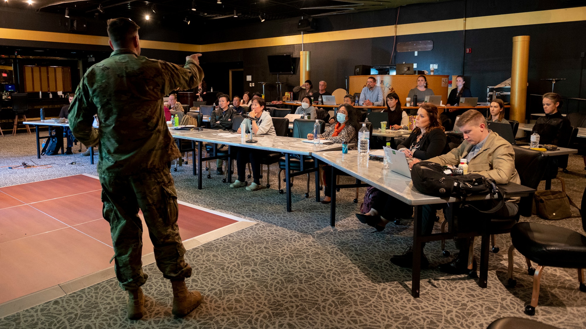 A man in a military unform stands in front of a seated crowd