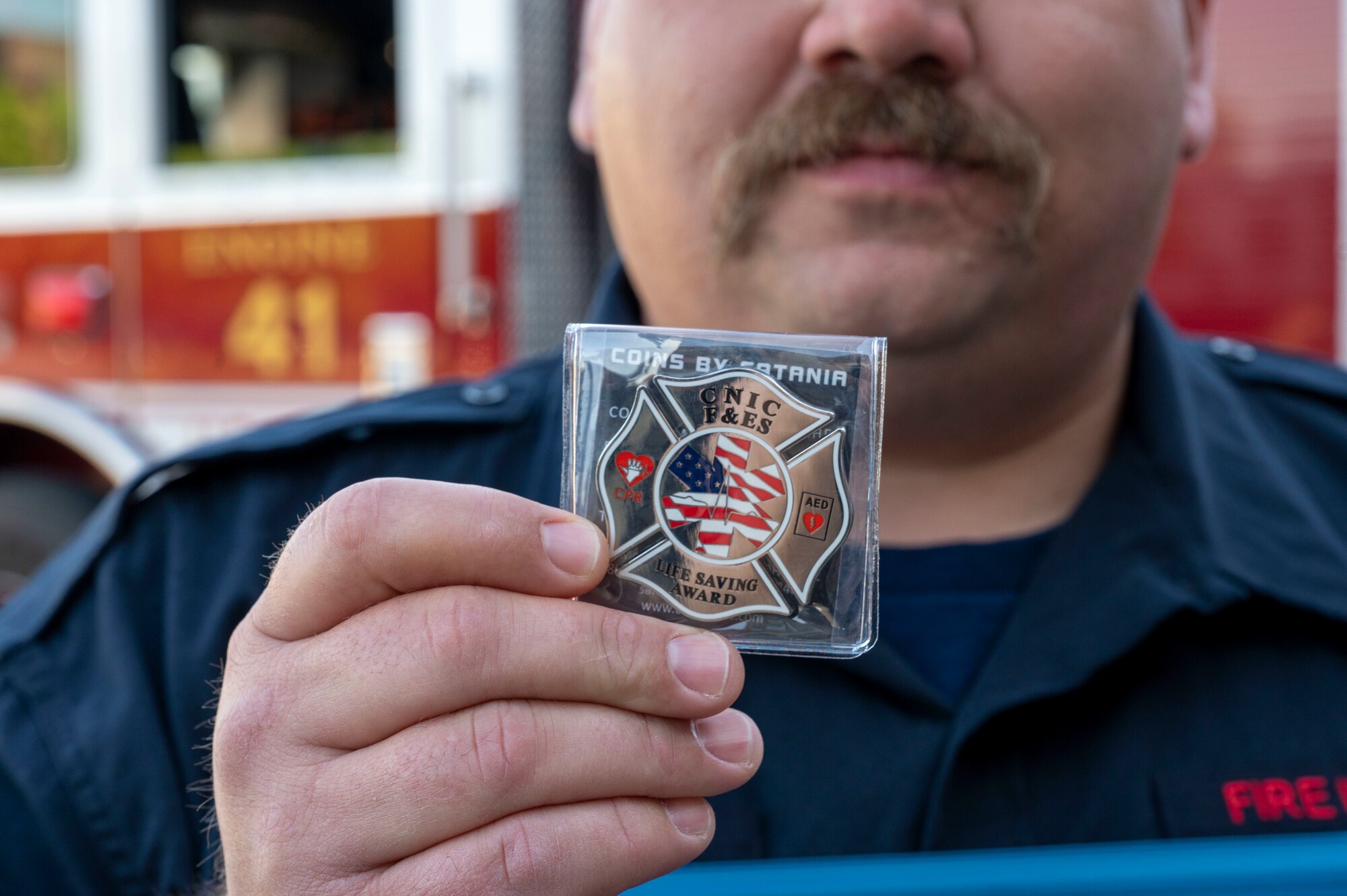 Fire Inspector Alexis Frye holds the Life Saving Award coin he was presented with at the Life Saving Award presentation, April 13, 2023, Joint Base Anacostia-Bolling, Washington, D.C. Members of Naval District Washington Fire and Emergency Services were recognized with Certificates of Life Saving and Significant Achievement for their quick response to an incident on JBAB which resulted in the patient’s second chance at life. (U.S. Air Force photo by Kristen Wong)