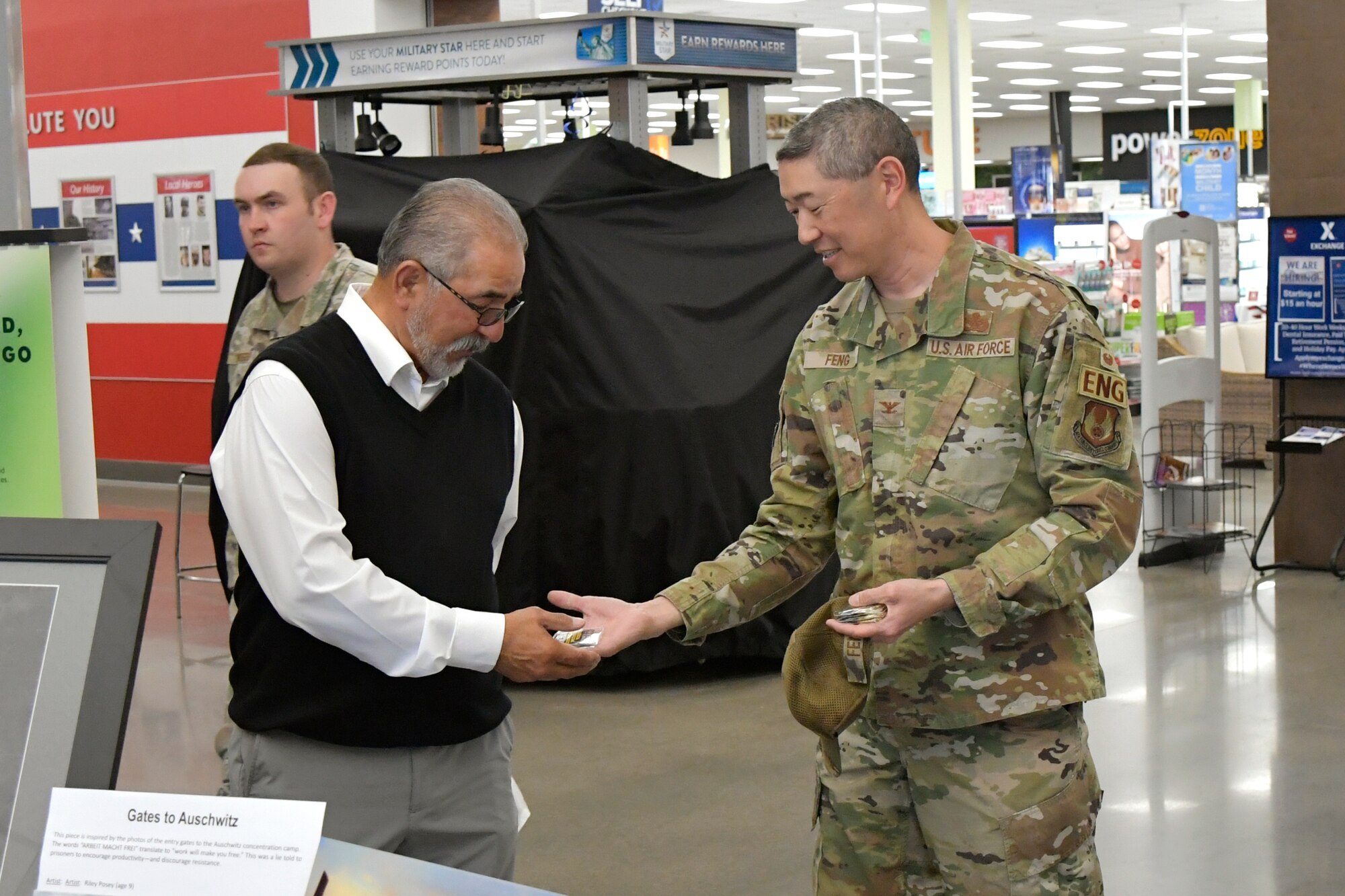 Left, Miguel Palomin, 75th Logistics Readiness Squadron, accepts a coin on behalf of his granddaughter Alissa Atkinson from Col. Peter Feng, 75th Air Base Wing vice commander, for Atkinson’s submission to the Holocaust Days of Remembrance art exhibit April 17, 2023, at Hill Air Force Base, Utah