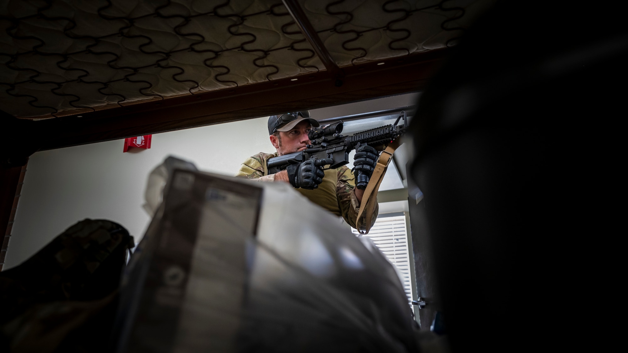 U.S. Air Force Tech. Sgt. Jason Evans, 56th Civil Engineer Squadron Explosive Ordnance Disposal flight technician, checks the scope of an M4 carbine assault rifle in a barracks bay at Camp Navajo, Arizona, April 10, 2023.