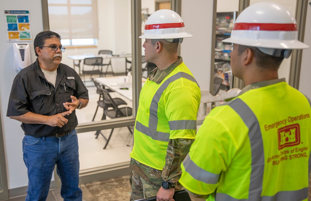 Staff Sgt. Alvaro Alzate, middle, and Sgt. Antonio Vargas, right, with the 249th Engineering Battalion speak with Mark Garcia, Galveston County Assistant Facilities Director, about the electrical power capabilities of the Bayside Community Center.