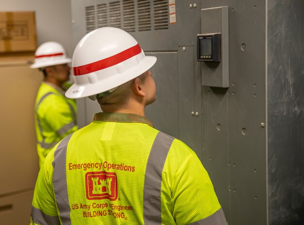Staff Sgt. Alvaro Alzate, front, and Sgt. Antonio Vargas, with the 249th Engineering Battalion, inspect electrical equipment in the Bayside Community Center.