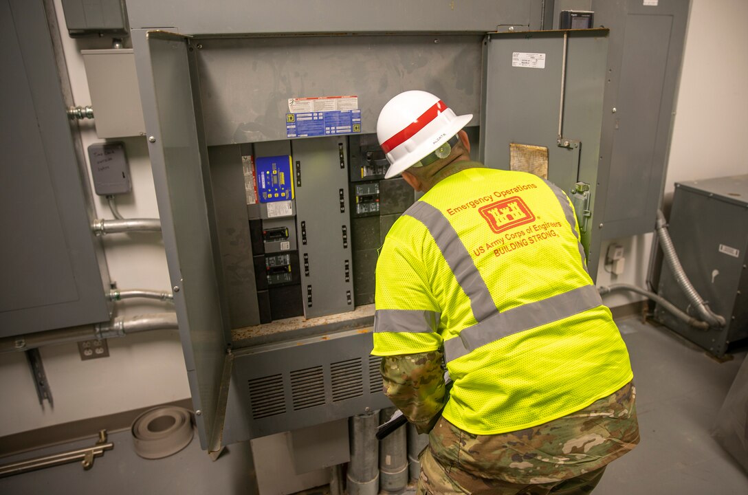 Staff Sgt. Alvaro Alzate, with the 249th Engineering Battalion, inspects a fuse panel in the Bayside Community Center.