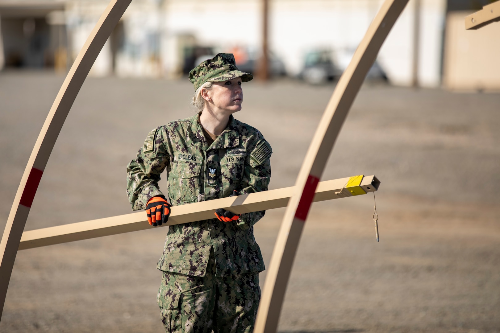 DLA Distribution Expeditionary reservist Petty Officer 1st Class Jennifer Xepoleas carries a frame part while setting up an Alaskan Shelter during the DLA Distribution Expeditionary Academy on April 19, at DLA Distribution San Joaquin. Photo by Julian Temblador.