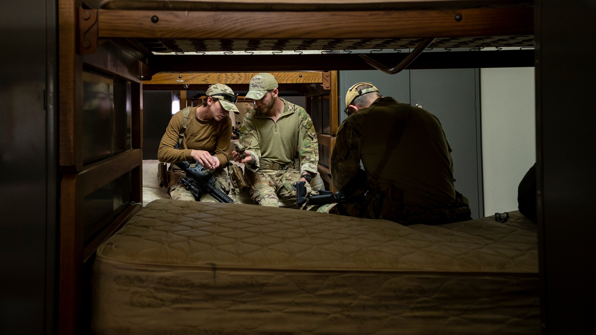 U.S. Air Force Airman First Class Brianna Mclain (left) and Airman First Class Jessey Mclain (center), 56th Civil Engineer Squadron Explosive Ordnance Disposal flight technicians, look over gear in a barracks bay at Camp Navajo, Arizona, April 10, 2023.